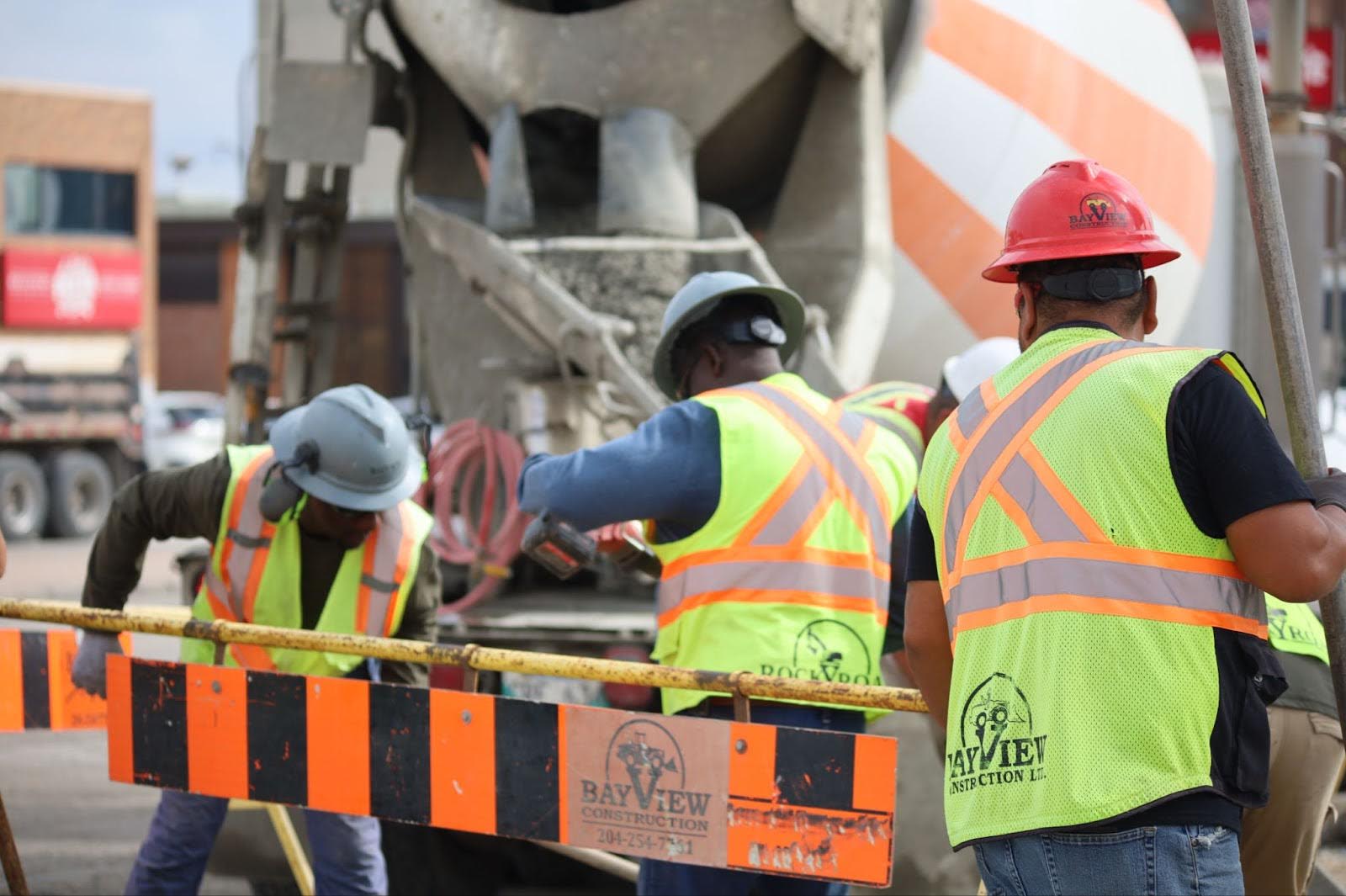 Des ouvriers de la construction portant des gilets haute visibilité et des casques de sécurité sur un site avec un camion.