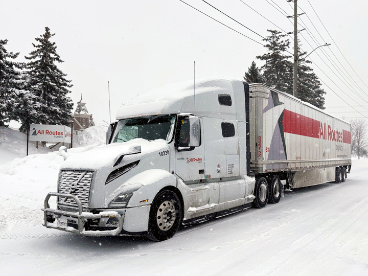 While All Routes Logistics truck on snowy street in front of yard
