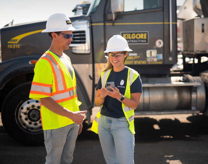 Two workers standing near a truck using the Samsara mobile experience