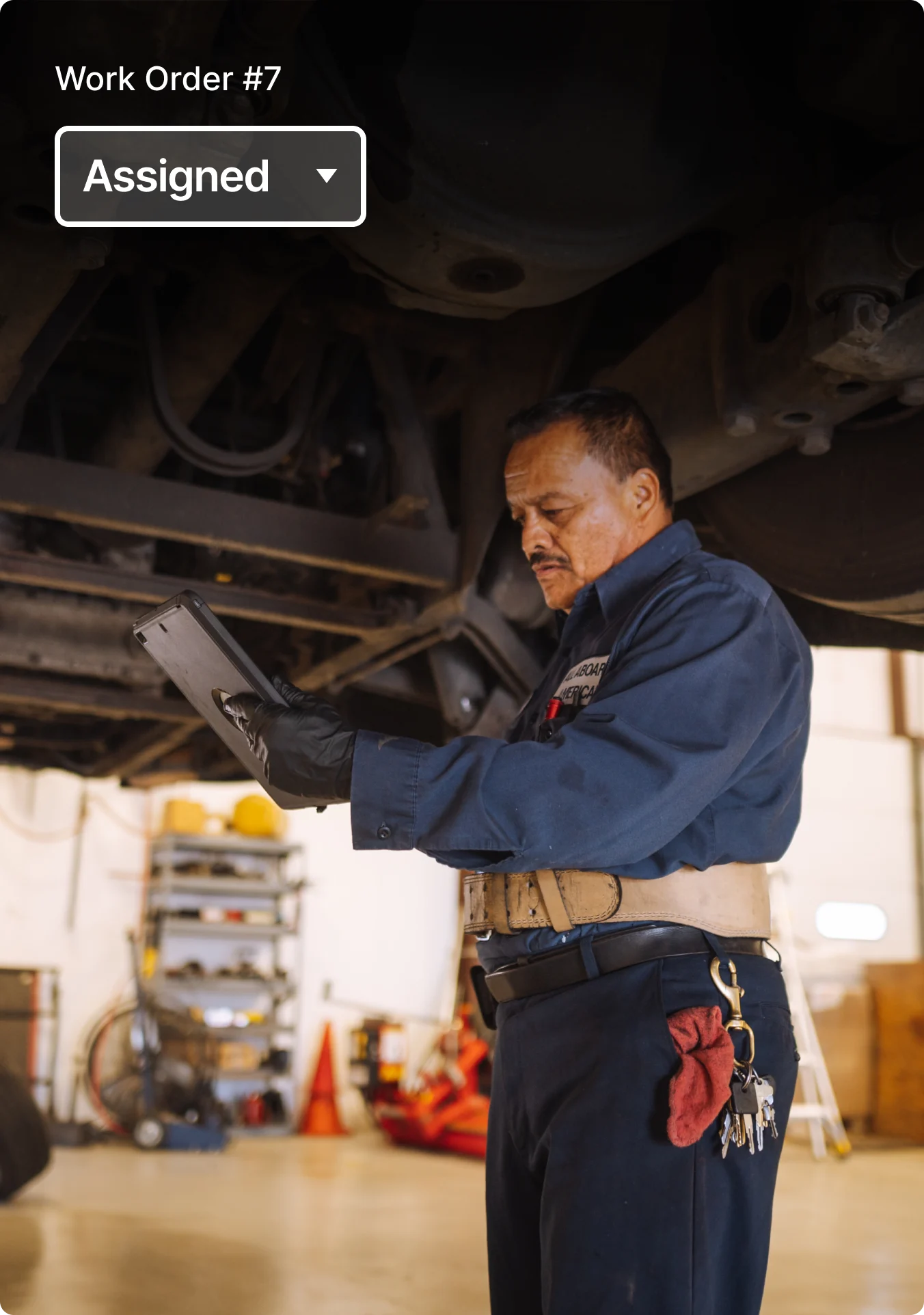 Two mechanics review work order status on a mobile phone.