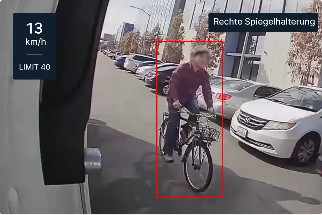 Dashboard-Straßenansicht mit Radfahrer und geparkten Autos; Geschwindigkeitsanzeige zeigt 13 km/h in einer 25-km/h-Zone.