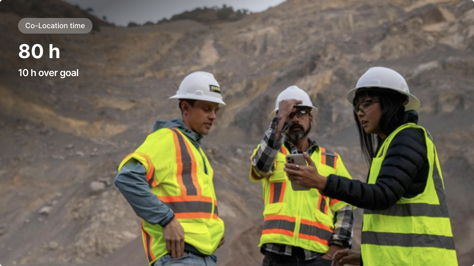 Three workers in hard hats and safety vests discussing at a quarry site, with '80h' co-location time displayed.