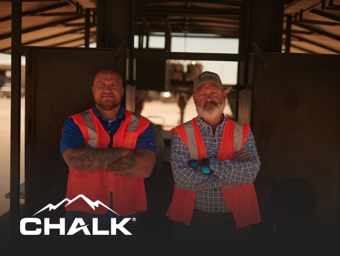 Two Chalk Mountain Services employees stand tall in front of onsite work site.
