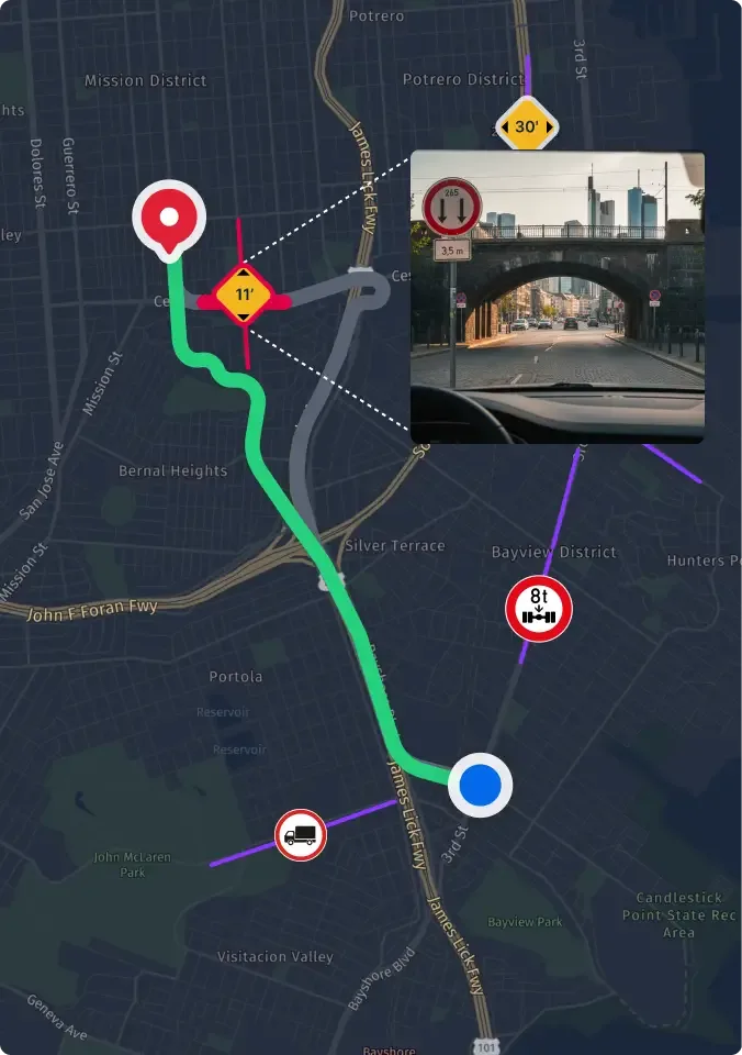 Schild mit Geschwindigkeitsbegrenzung am Straßenrand, Gebäude im Hintergrund, gesehen aus Fahrzeug mit Seitenspiegel.
