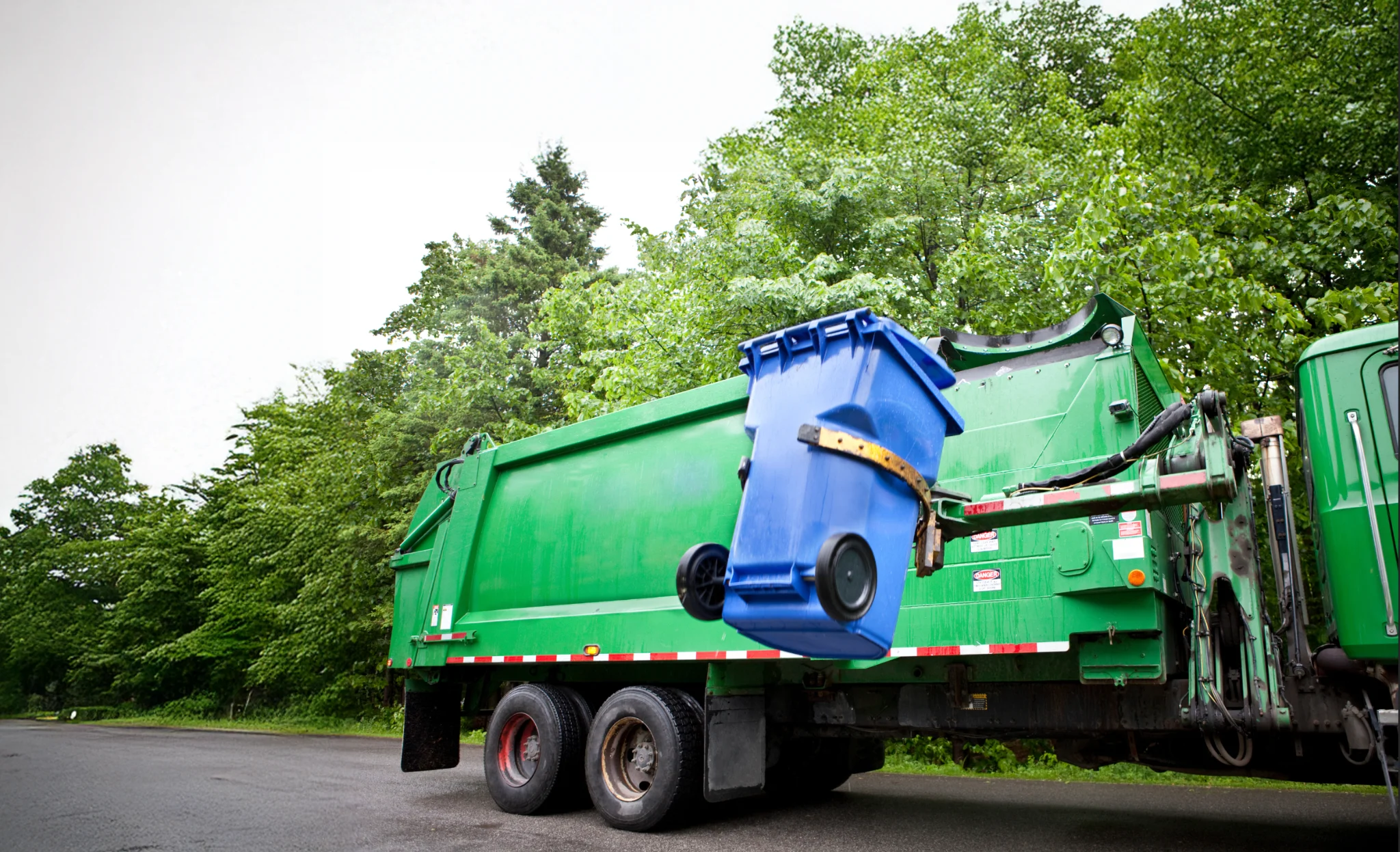 Sanitation workers throwing bags of garbage into a garbage truck