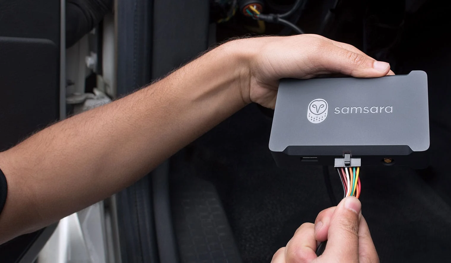 Person holds Samsara Vehicle Gateway 34 product plugging in vehicle connector cables.