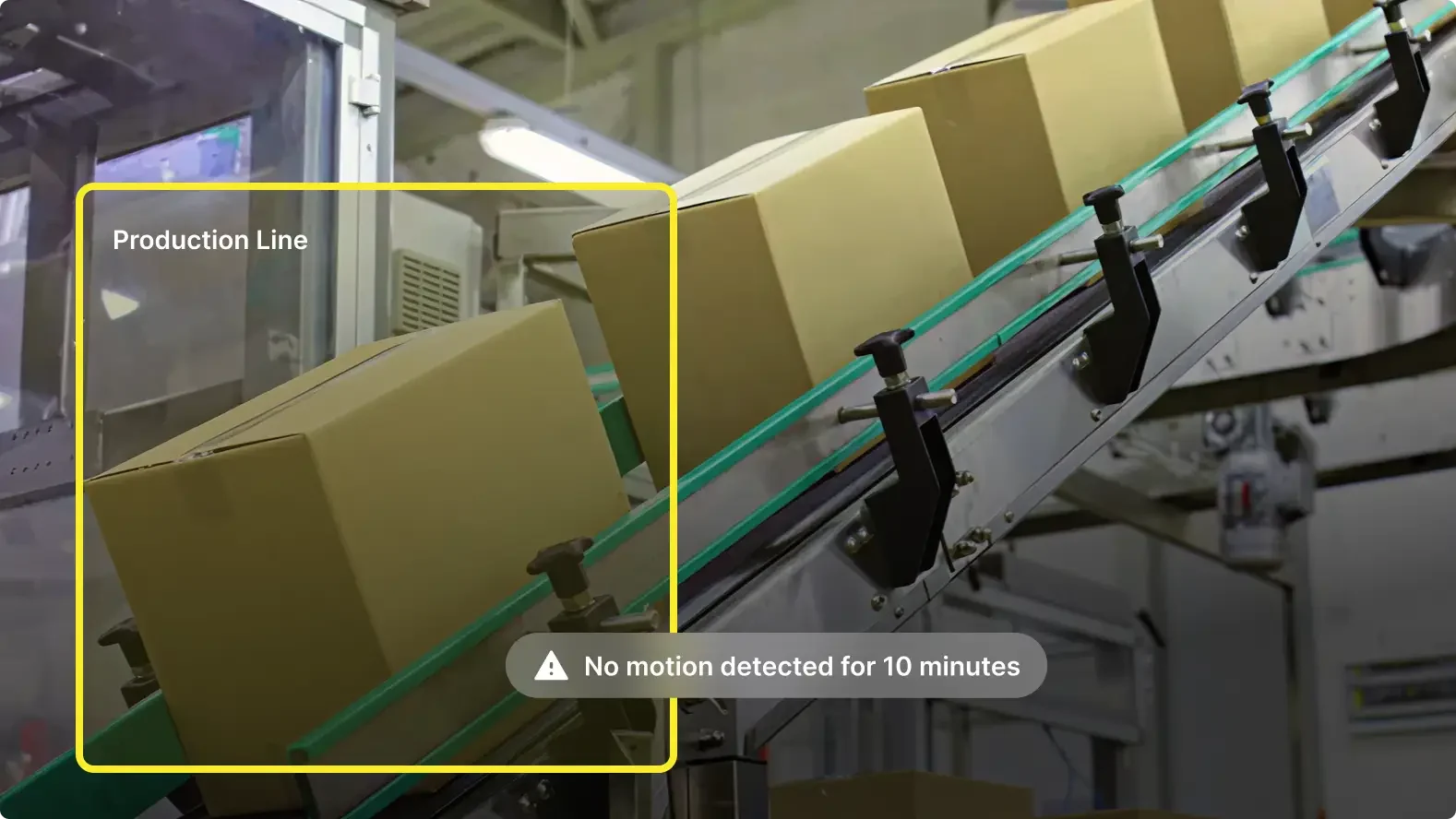Cardboard boxes on conveyor belt in manufacturing facility with alert showing no motion detected for 10 minutes