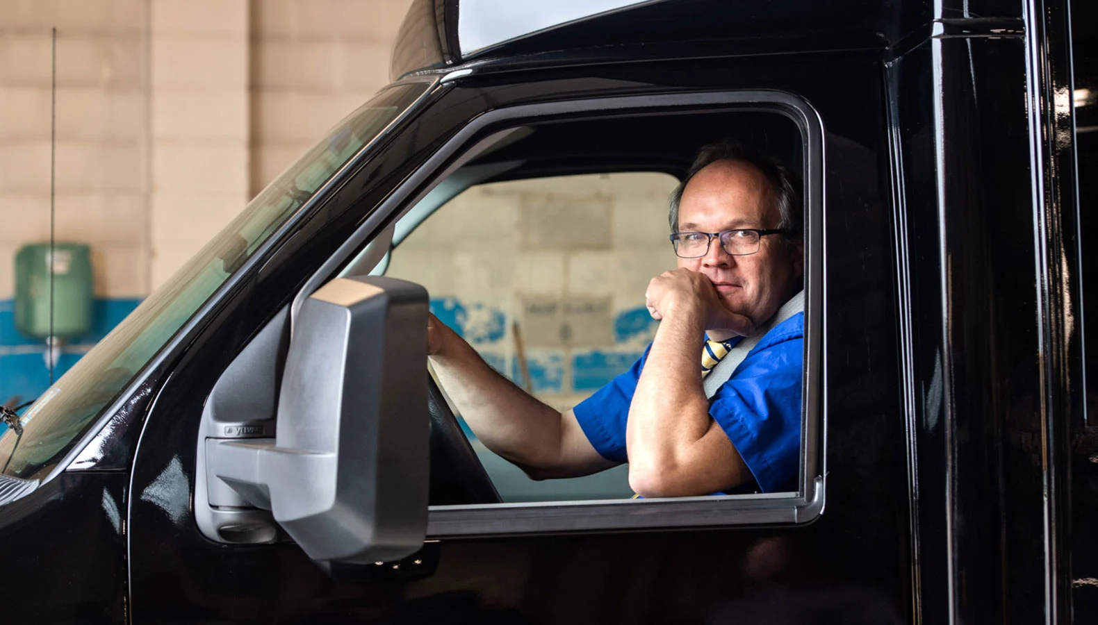 Person sitting in the driver seat holding and looking at a tablet.