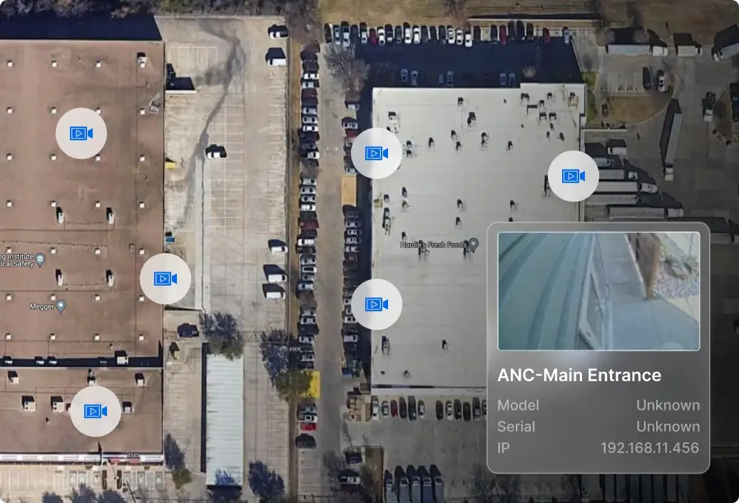 Aerial view of commercial buildings with parking lots and security camera interface showing ANC-Main Entrance camera feed.