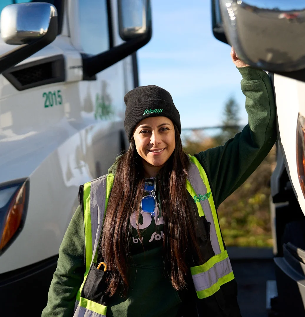 a sobeys employee looking at the camera and smiling while standing beside of a sobeys truck