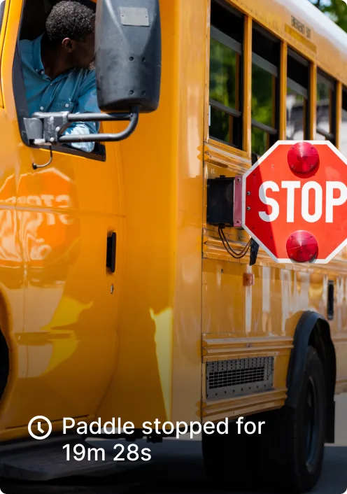 Yellow school bus with extended stop sign showing driver in blue shirt at the wheel.