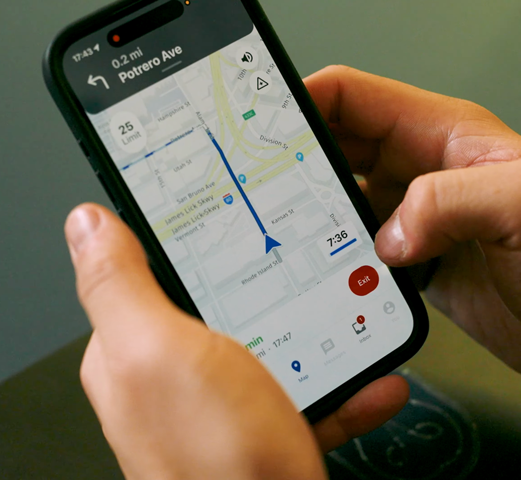 Hands holding a smartphone displaying a navigation app with a blue route map directing toward Potrero Ave.