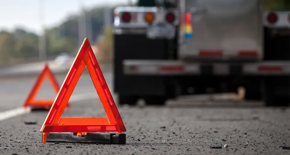 Orange warning triangles placed on a road near a stationary truck