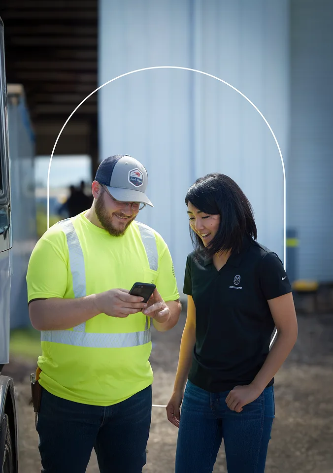 Smiling Samsara customer with Samsara employee looking at phone