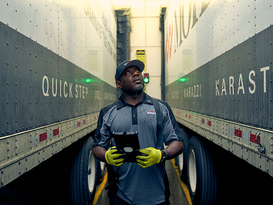 Worker standing between trailers using a mobile device