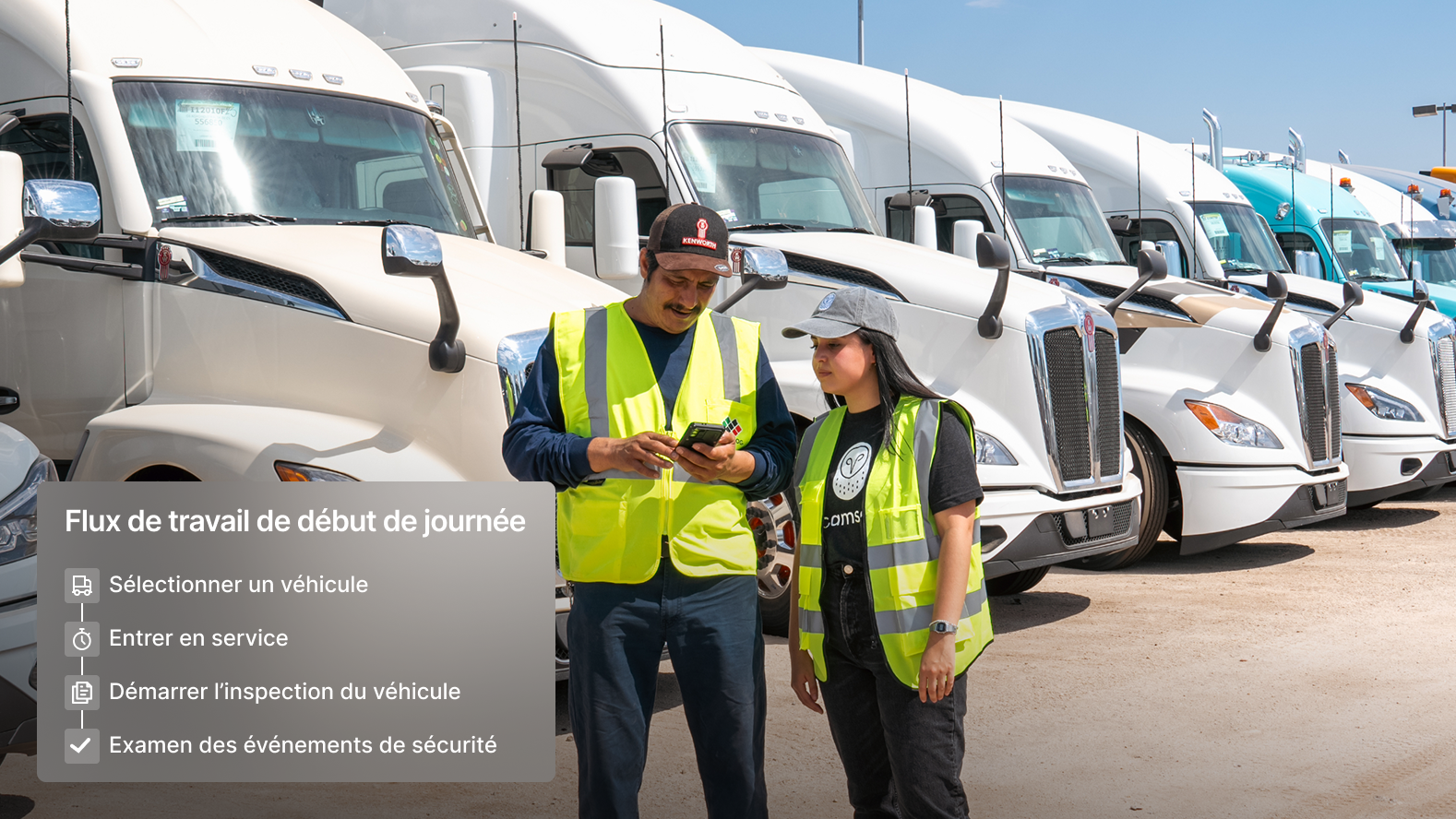 Deux conducteurs regardant un téléphone devant une flotte de camions