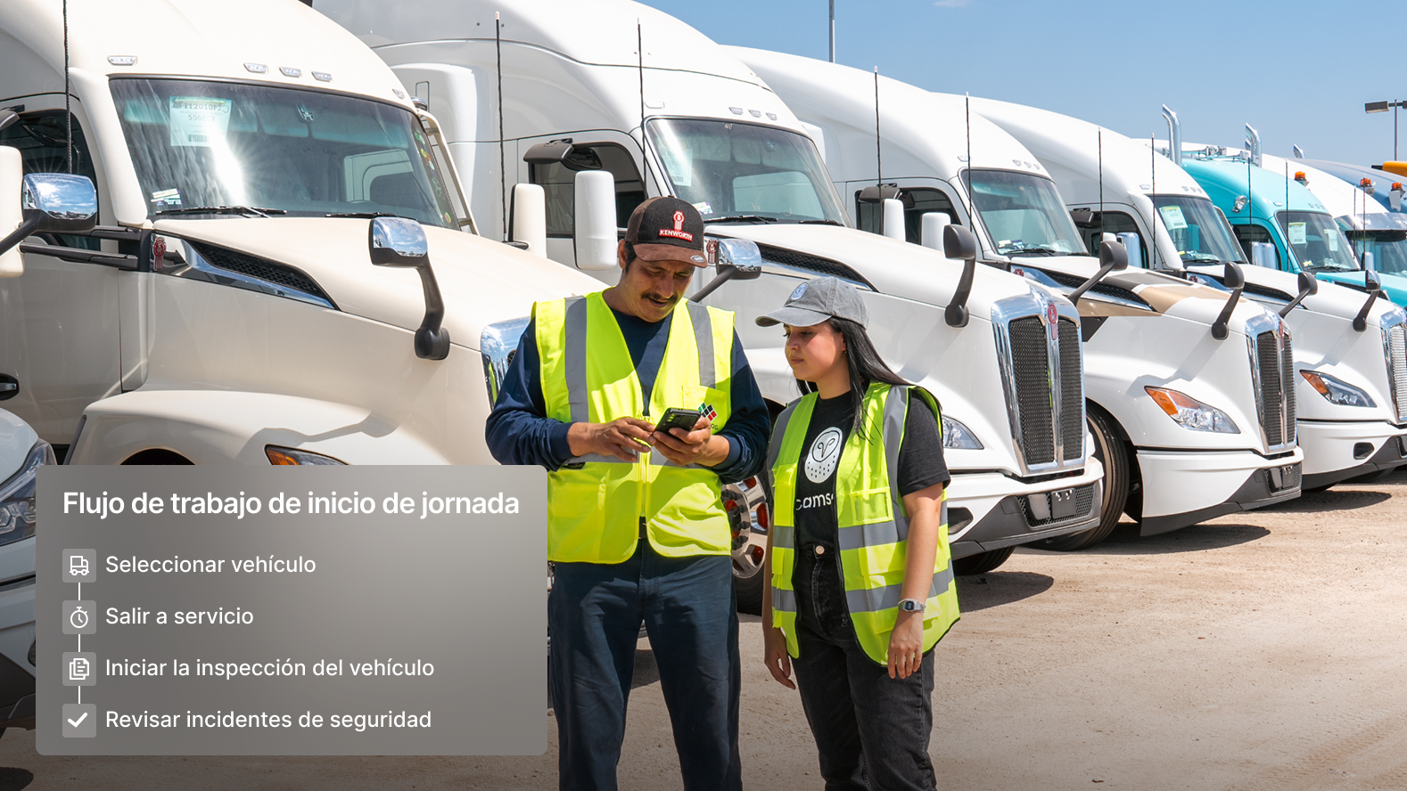 Dos conductores mirando un teléfono frente a una flota de camiones
