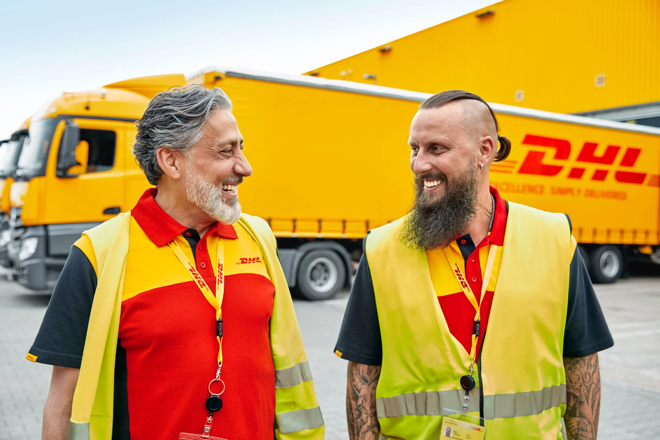 Deux conducteurs de camion se tiennent l'un à côté de l'autre et se regardent, camion en arrière-plan.