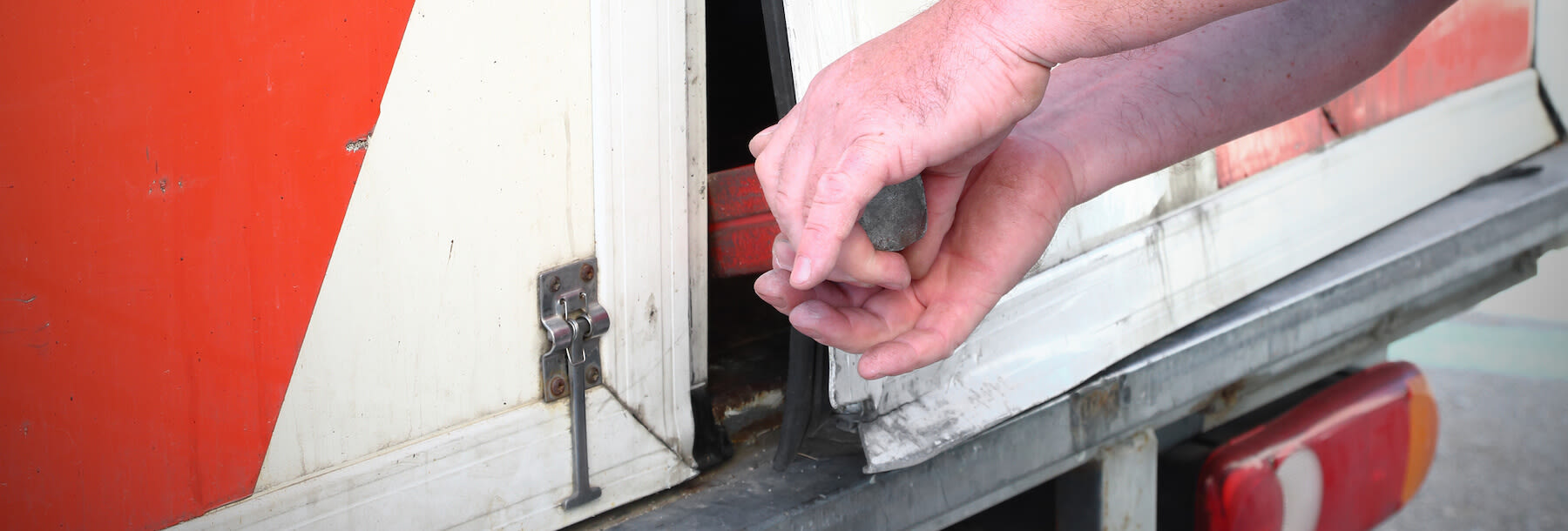 Man breaking into the back of a truck door. 