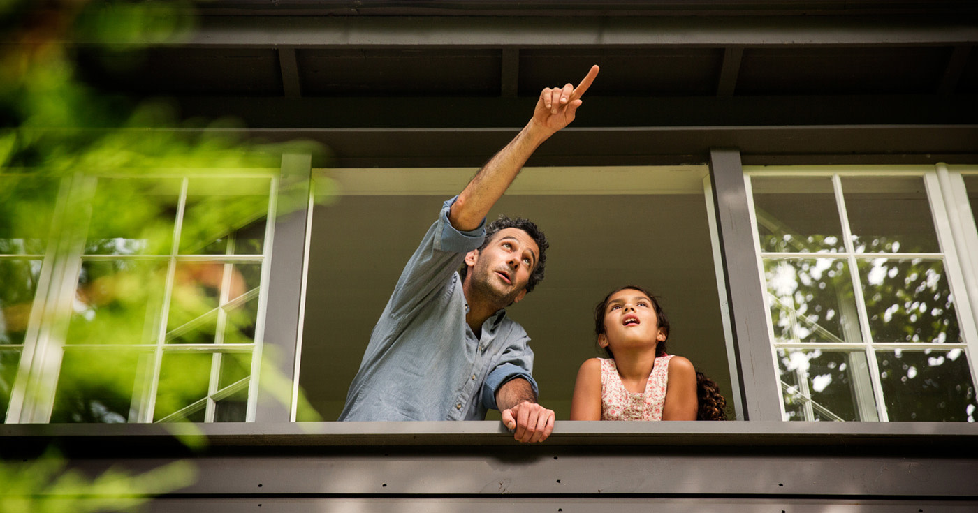 Man Pointing Next to a Child  Outside of a Large Open Window