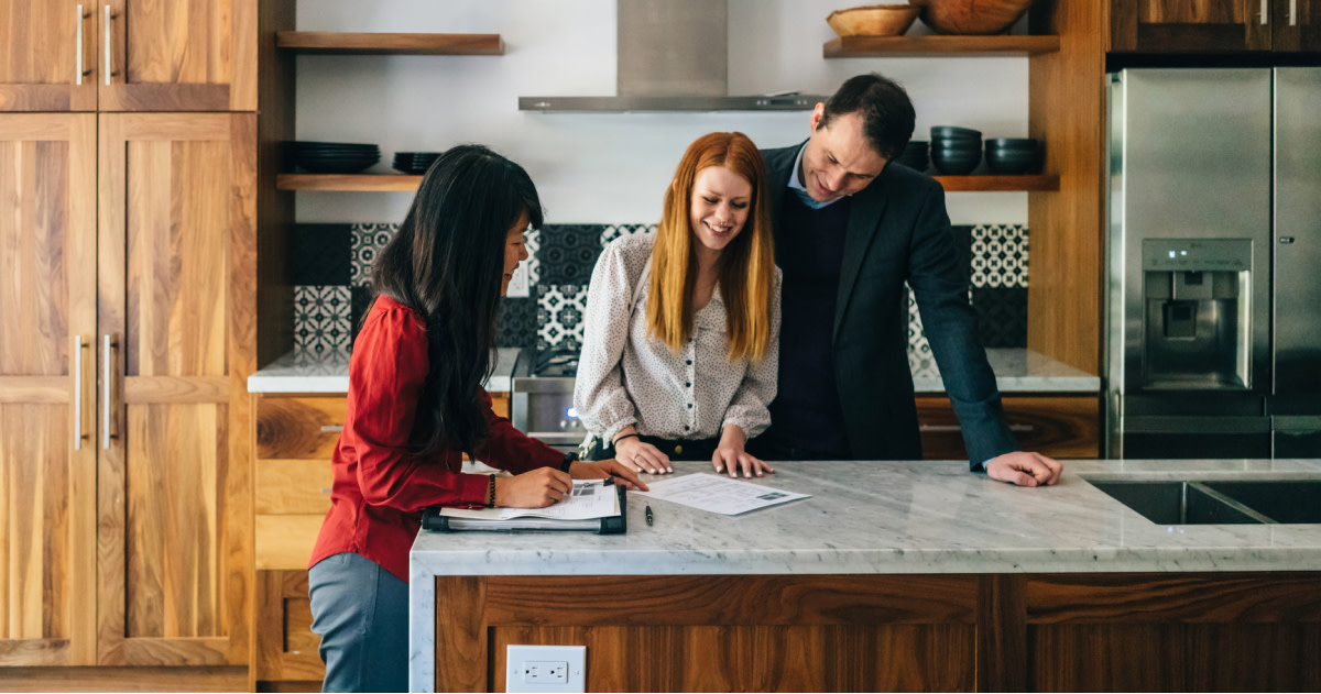 Man and Women Signing a Closing Document while a Real Estate Agent Oversees