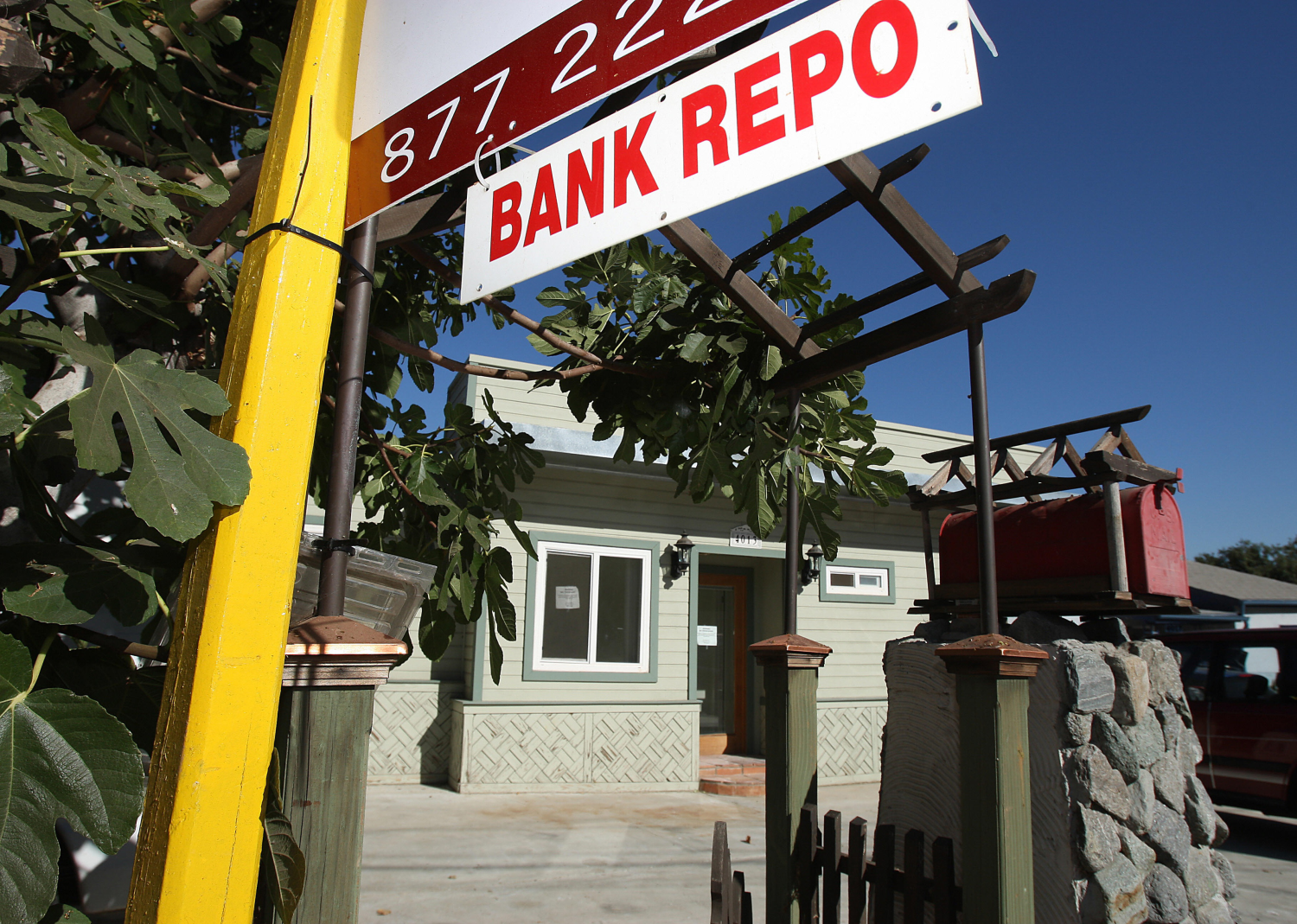 Low-angle photograph of a “BANK REPO” sign in front of a home - ROBYN BECK // Getty Images