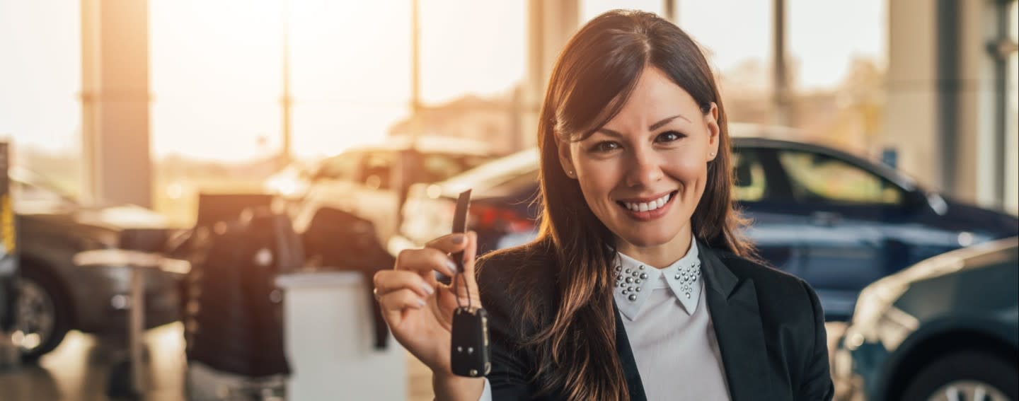 woman-holding-keys-to-a-new-car-at-a-dealership