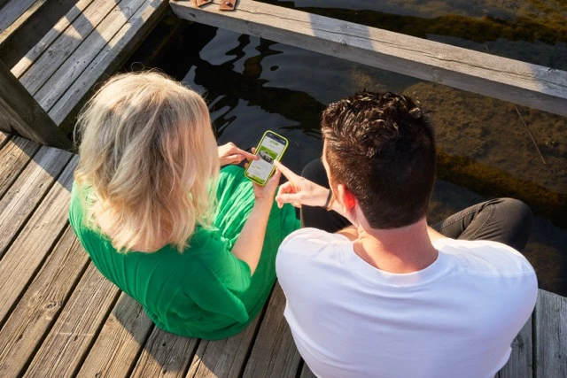 Kaksi henkilöä valitsemassa autoa puhelimen näytöltä