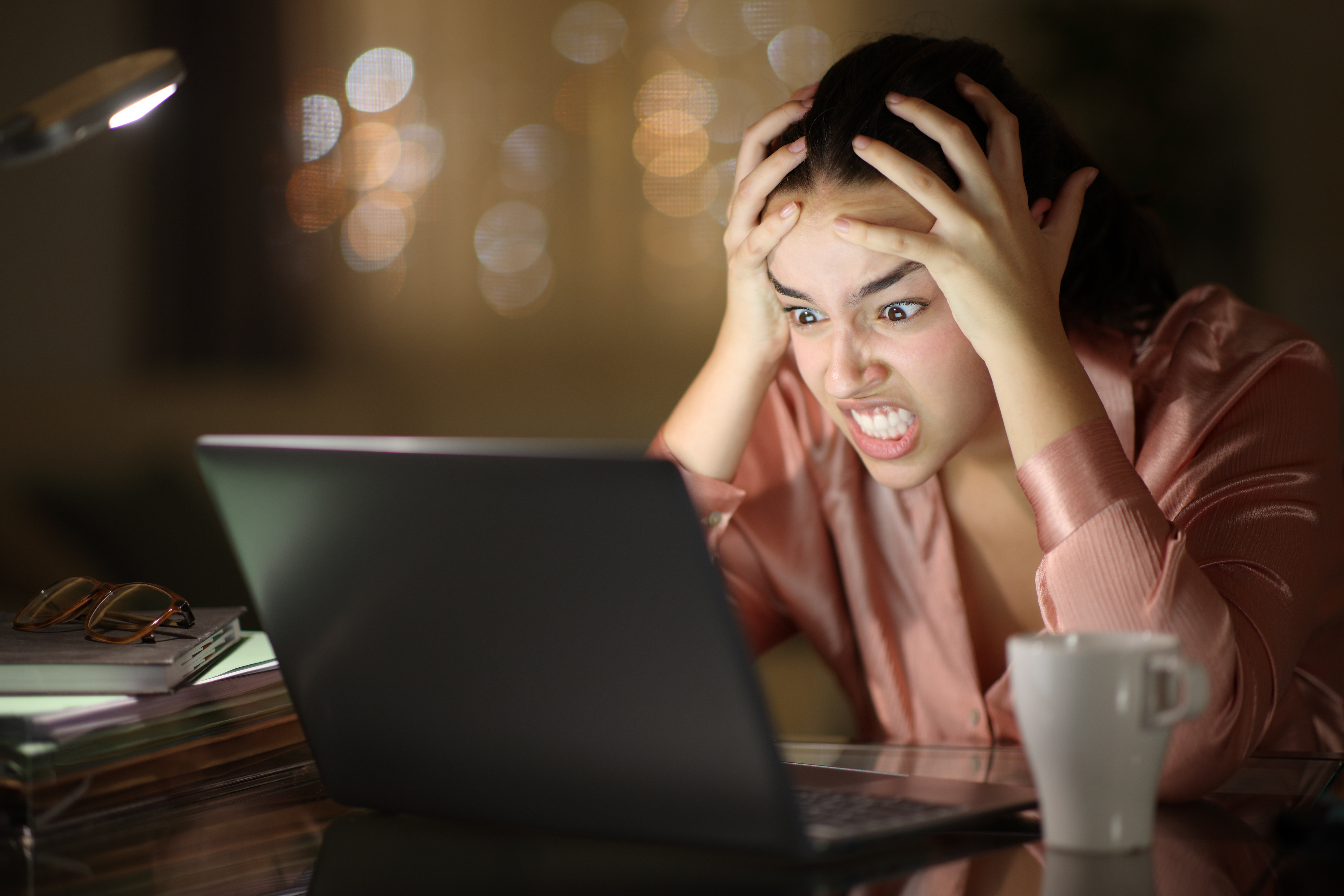 Frustrated, angry worker at laptop at night