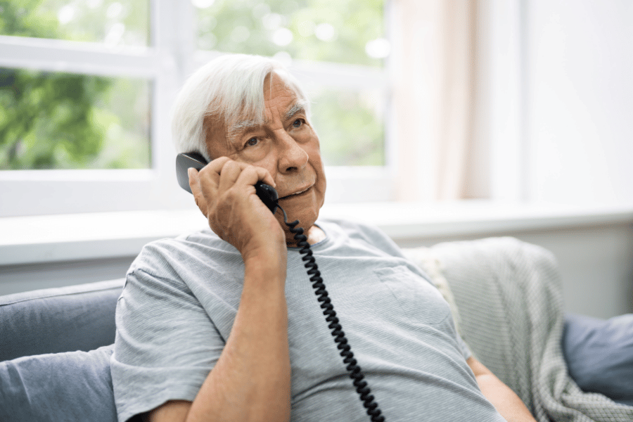 Older man at home making landline telephone call