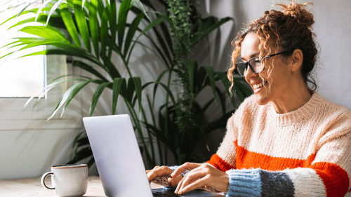 Happy woman with glasses on laptop in home office workspace