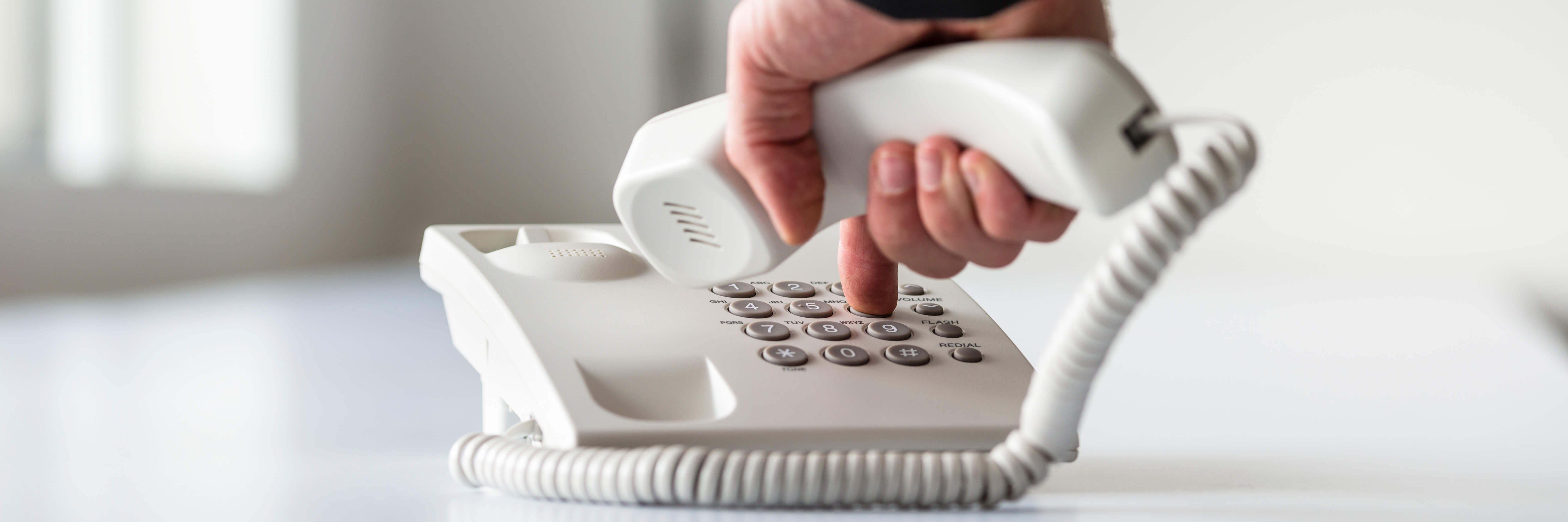 Male hand dialling a landline telephone