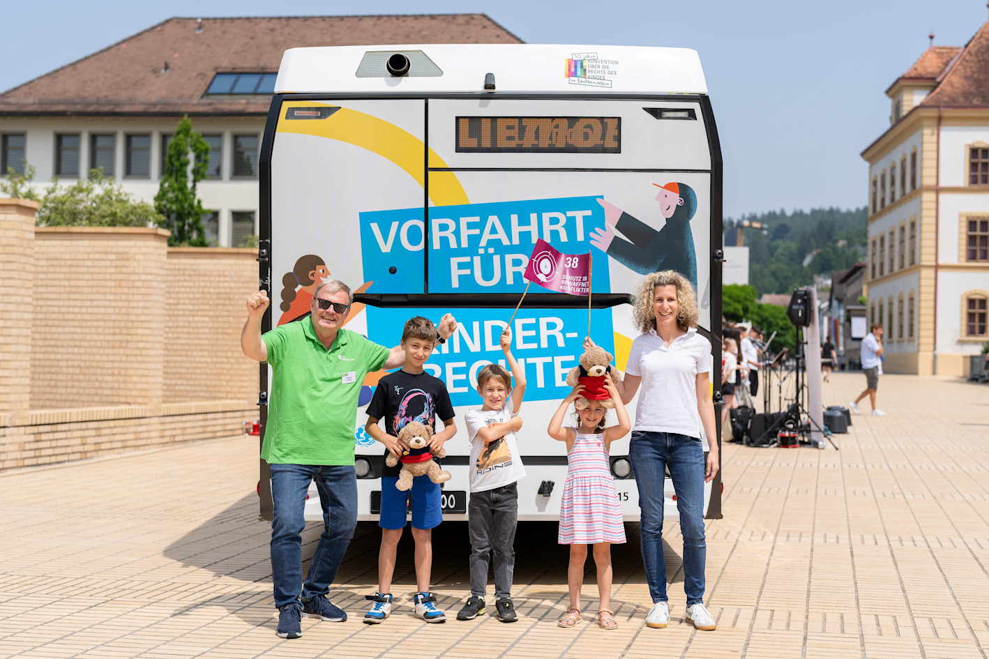 Markus from SOS Children's Villages and Maike with her children in front of the LieMobil bus with a flag promoting children's rights.