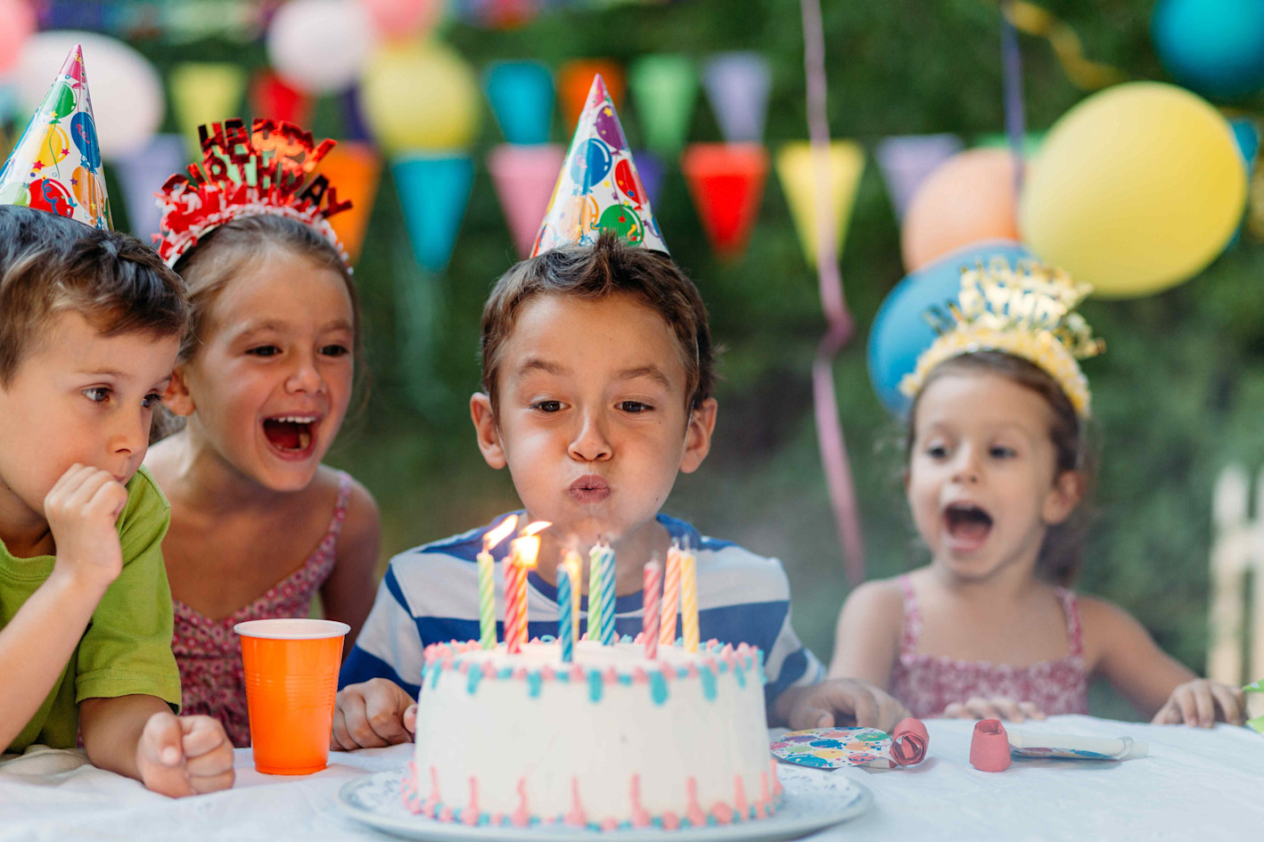 Kinder im SOS-Kinderdorf freuen sich über den Geburtstagskuchen und pusten die Kerzen aus. 