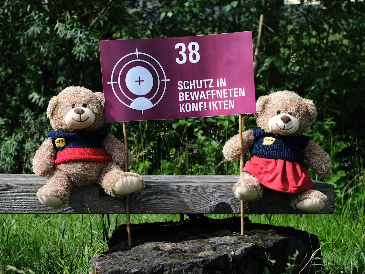 Teddys mit Kinderrechte-Plakat: Schutz in bewaffneten Konflikten 