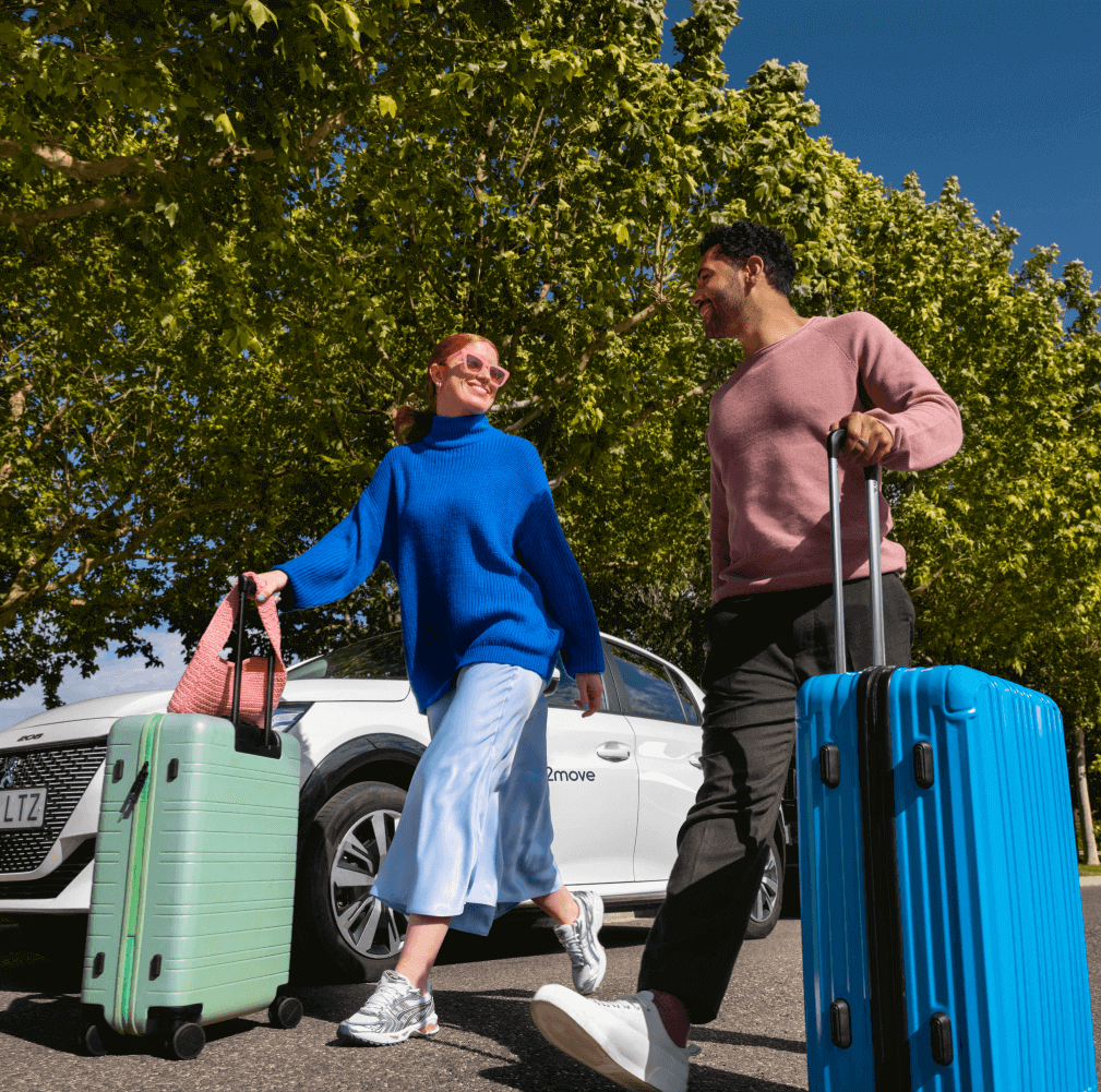Couple content avec des bagages devant une Peugeot blanche