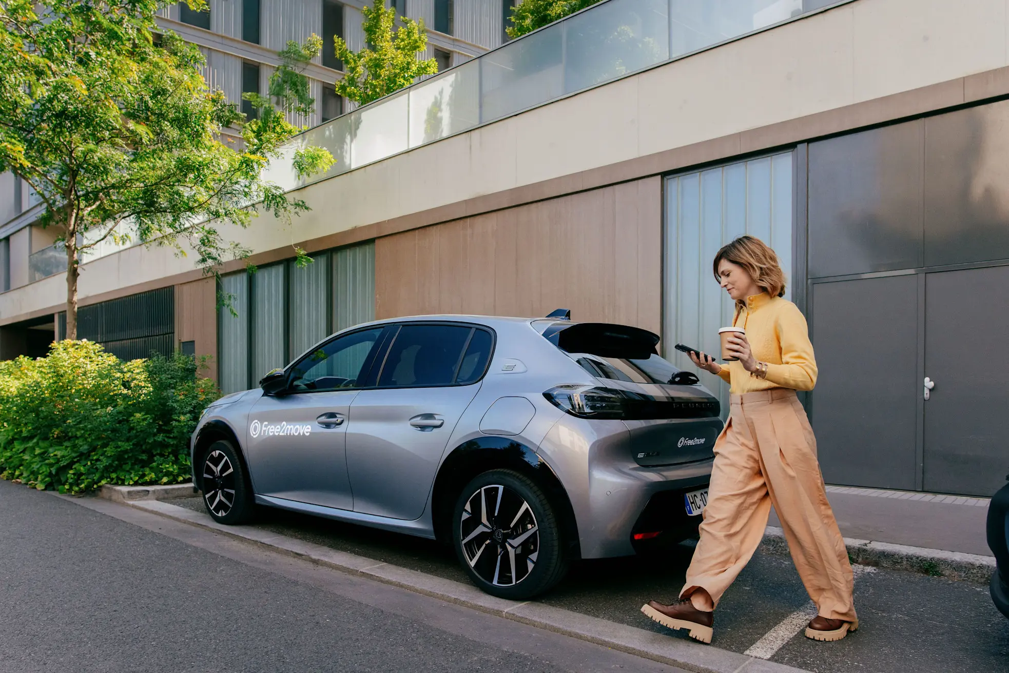 Frau mit einem Gepäckstück, die nahe an einem Free2move-Auto steht