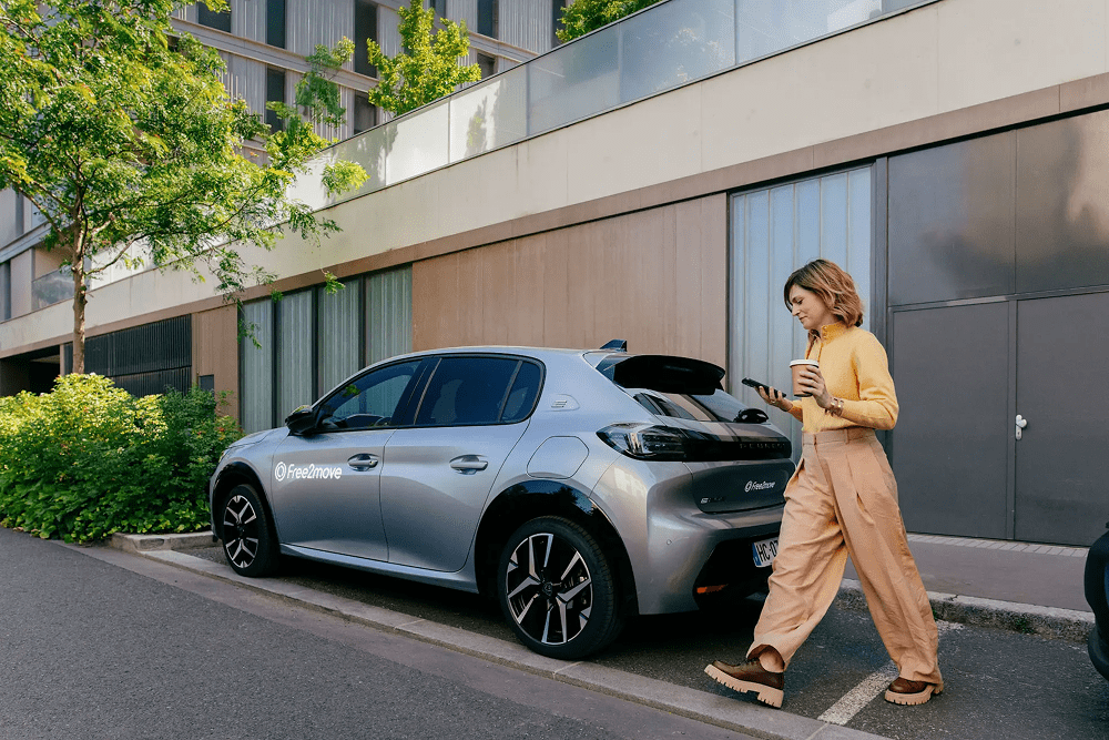 Frau mit einem Gepäckstück, die nahe an einem Free2move-Auto steht