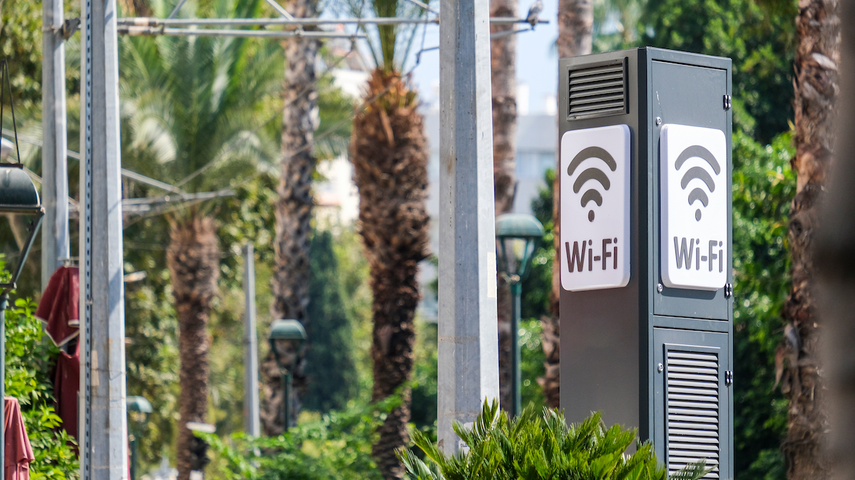 A signpost depicting wifi, surrounded by trees and greenery.