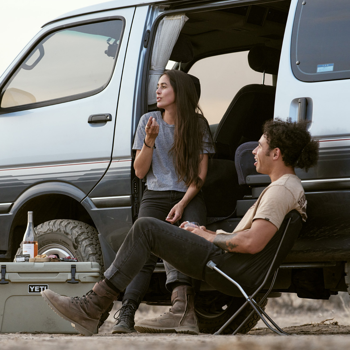 Couple sitting outside van eating a light meal.