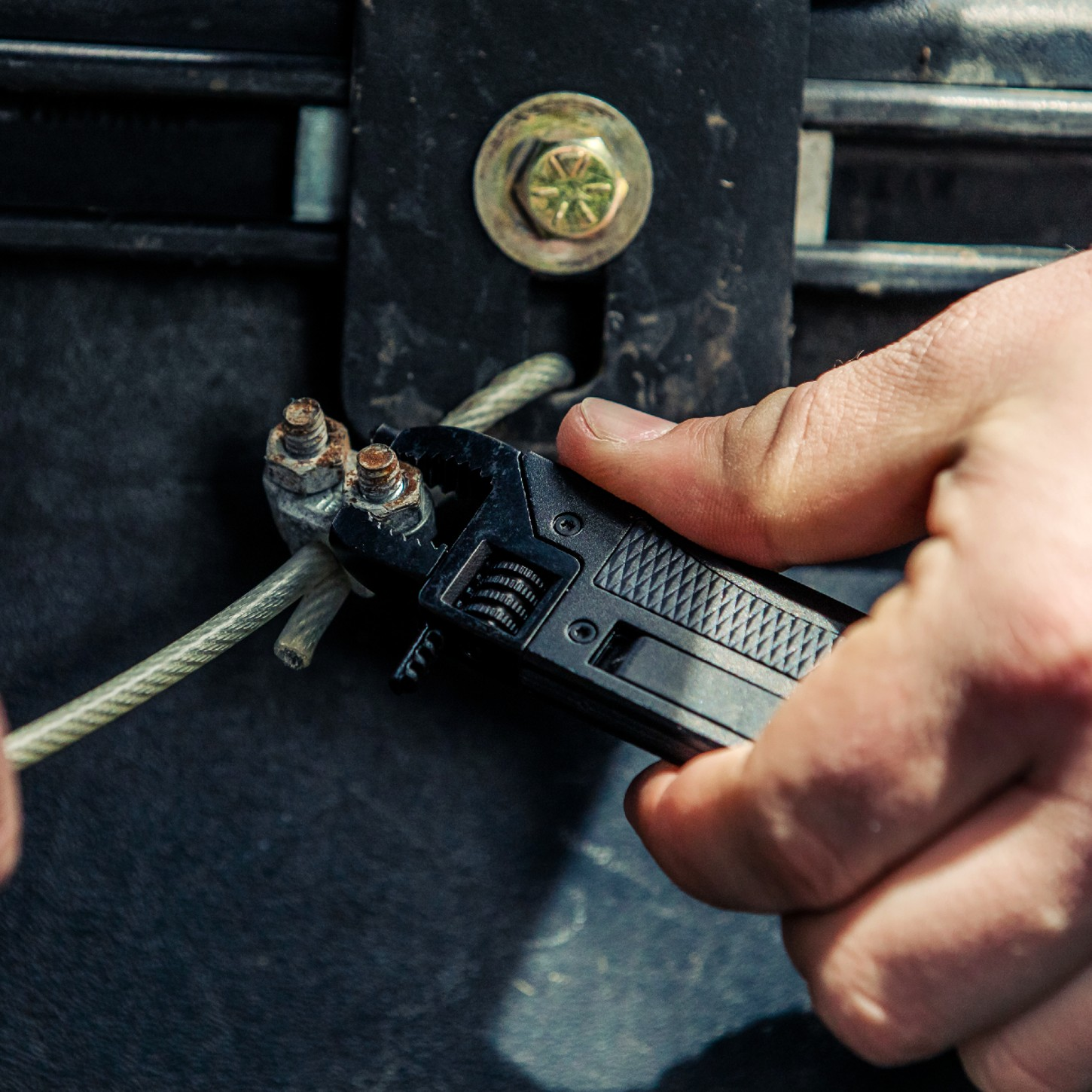 Close up of man using the wrench end of a knife to tighten a bolt.