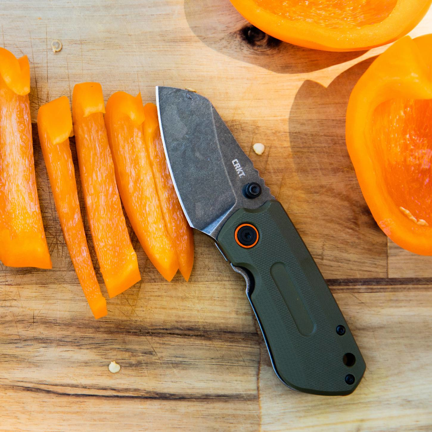 CRKT Knife on cutting board surround by peppers.