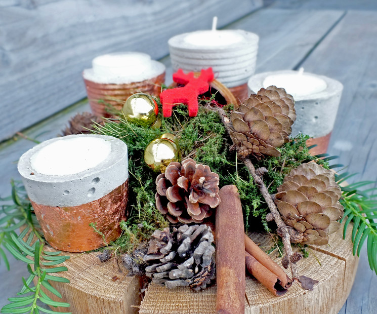 Adventskranz auf Holzscheibe mit Kerzen, Moos, Zapfen und weihnachtlicher Dekoration