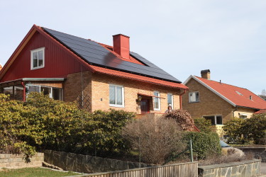 Rose-Marie framför sitt hus med nymonterade solceller på taket