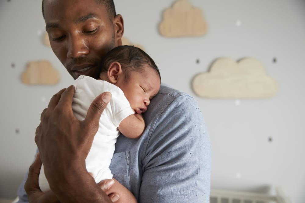 Young father holding his baby in his arm before bedtime