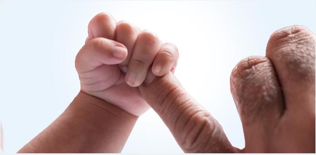 Baby holding parent's pinky finger