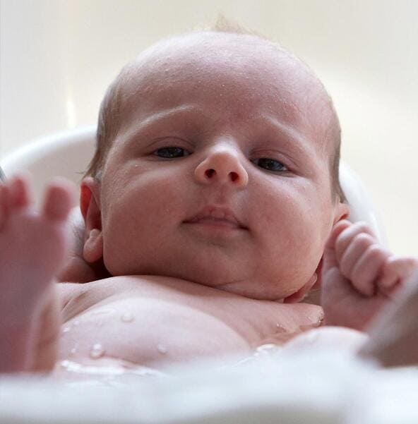 Newborn baby taking a bubble bath