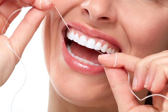 Young woman flossing her teeth 