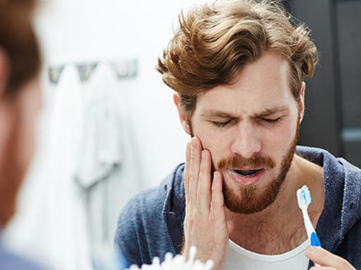 réflexion dans le miroir d'un homme qui porte sa main à sa joue