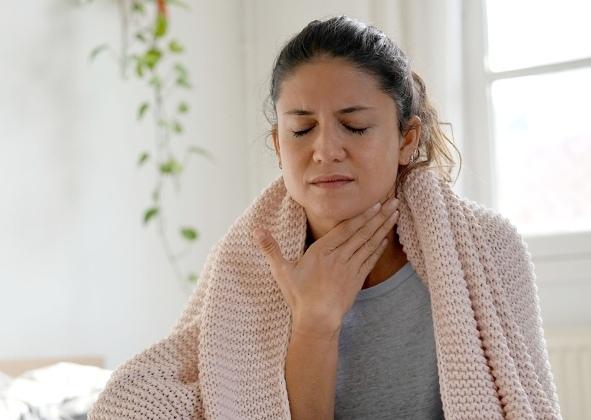 Femme emmitouflée dans une couverture et qui se touche la gorge